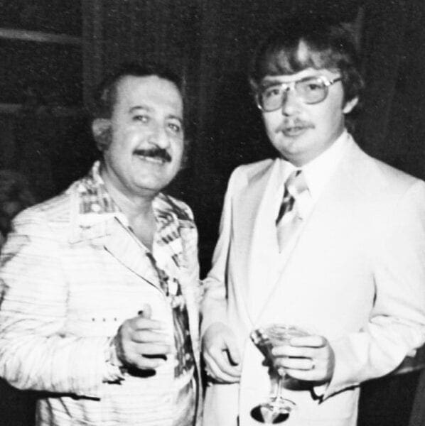 A black and white photo of two men at a cocktail party.