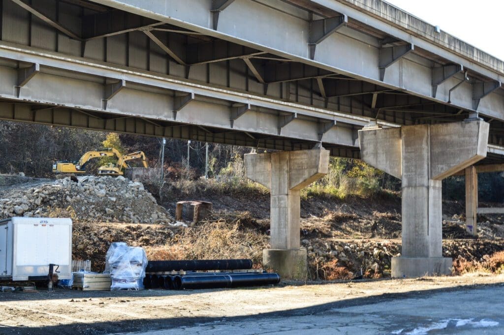 A photo under an interstate that reveals construction work along a creek.