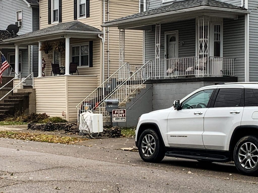 A house with a "For Rent" sign in front of it.