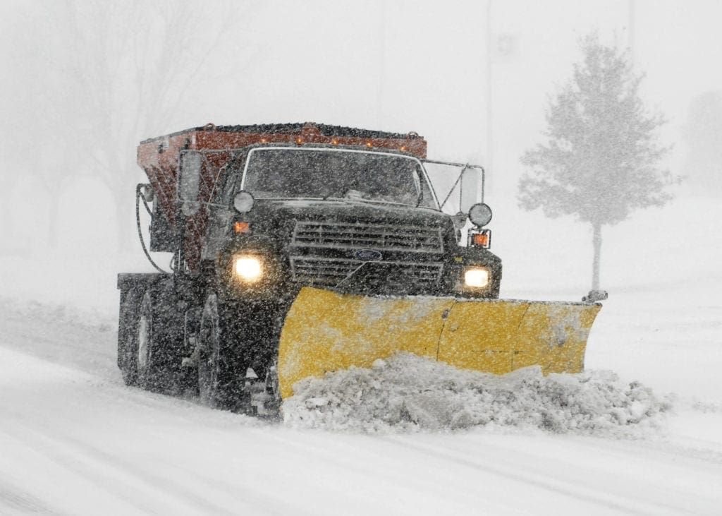 A large truck plowing a snowy road.