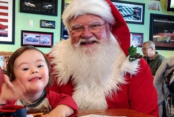 Santa Claus posing with a smiling child.