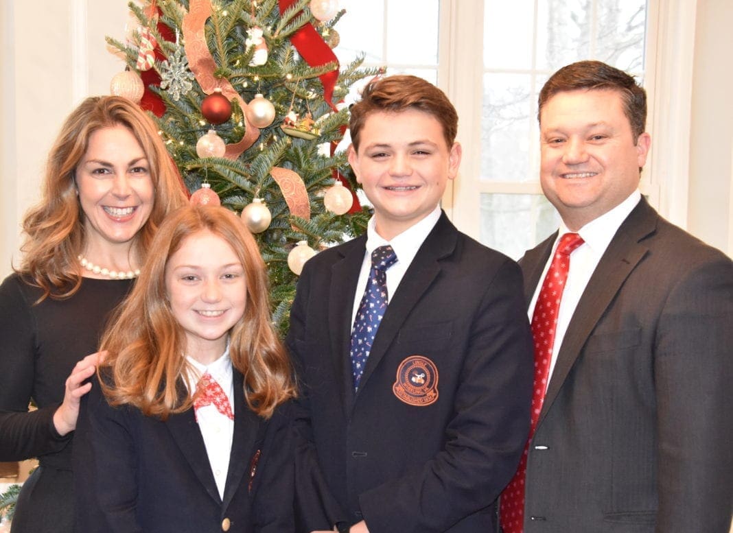 A photo of a family with a Christmas tree behind them.