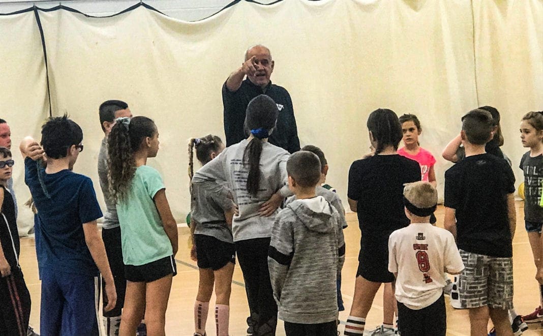 A coach speaking with a plethora of children.