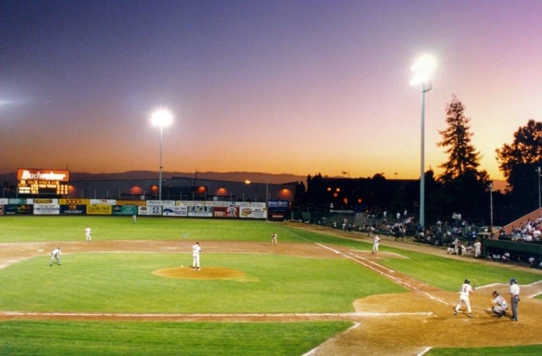 A minor league ballpark with the lights on.