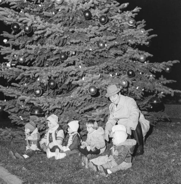 The mayor of a town lighting a Christmas tree with kids.