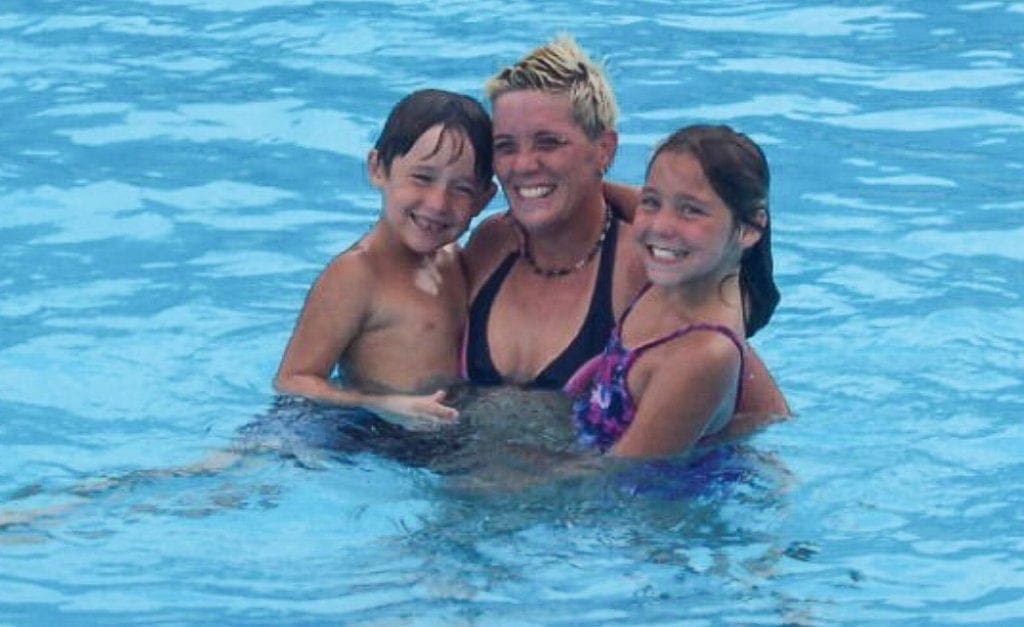 A photo of a mom with her son and daughter.