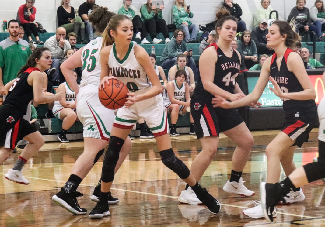 A female basketball player dribbles the ball up court.