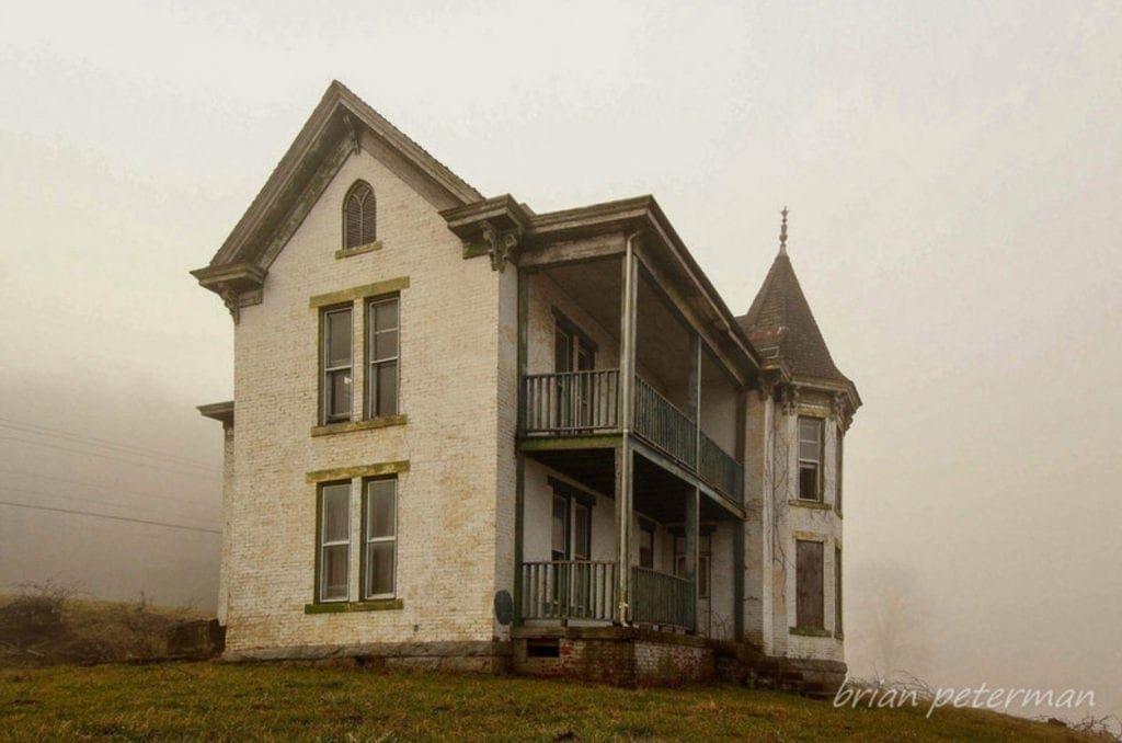 A photo of an old farmhouse in the middle of nowhere.