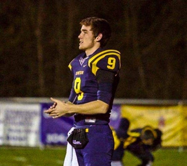 A football player on the sidelines without his helmet.