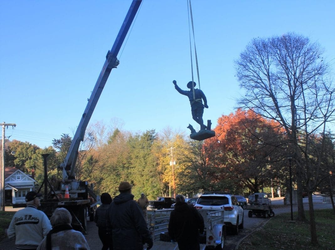 A crane lifting a doughboy statue for restoration.