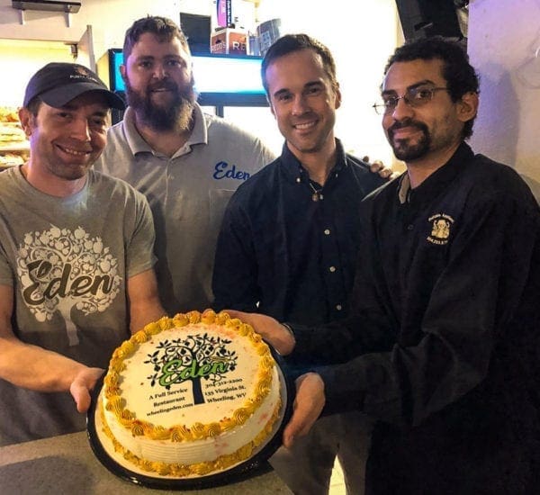 A group of men around a cake.