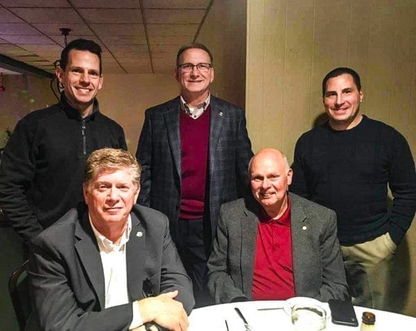 A photo of five men at dinner.