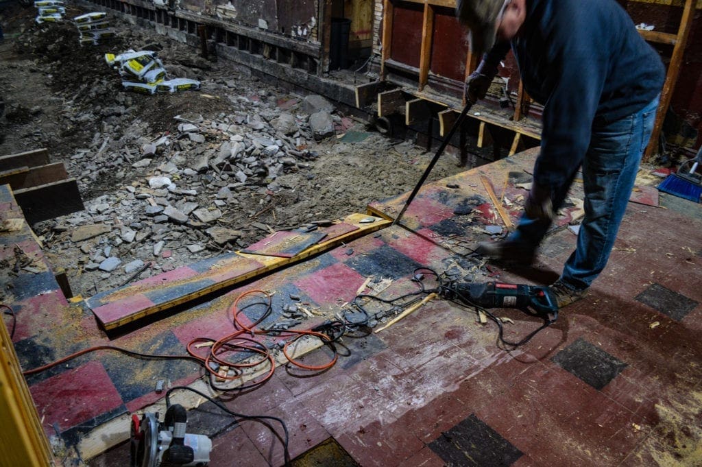 A worker tearing out a floor.