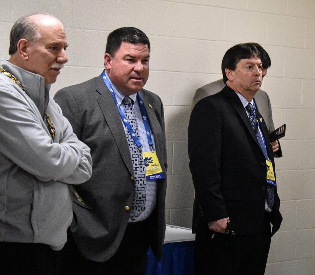 A photo of three men making an announcement.