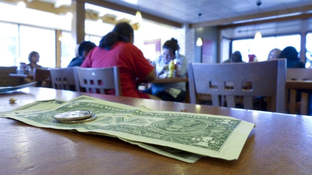 A photo of a few dollar tip on a bar.