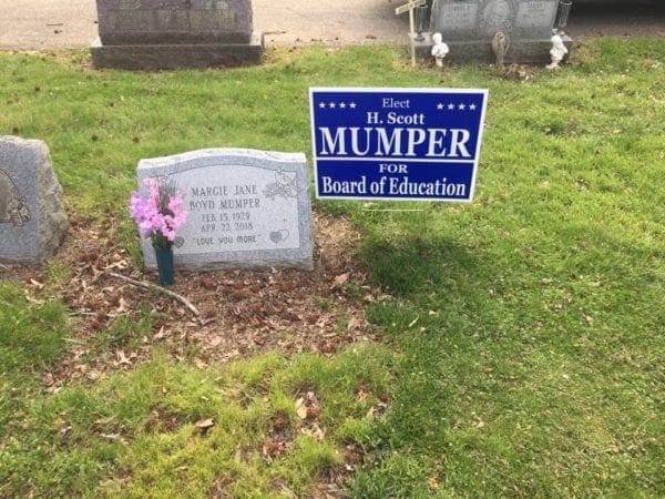 An election sign near a grave site.