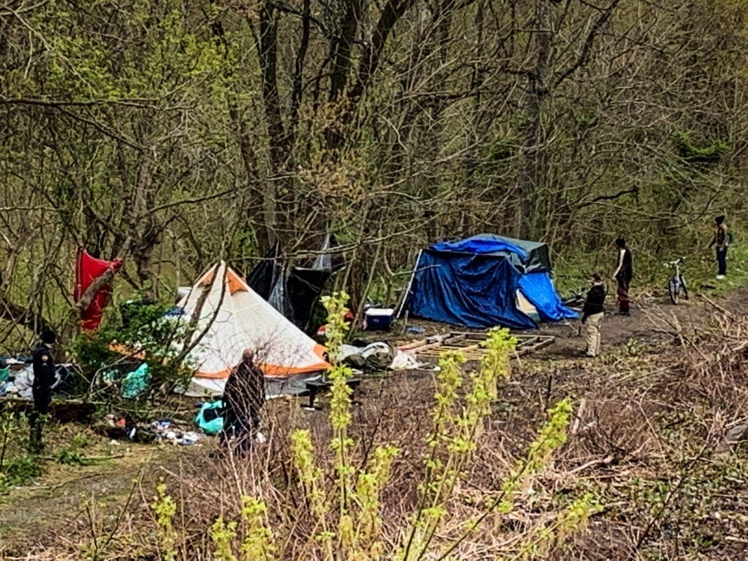 People standing around a homeless encampment.