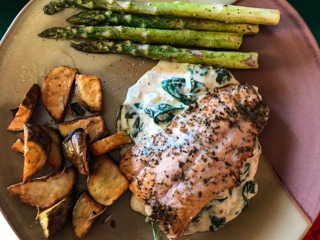 A dinner plate with spinach and salmon.