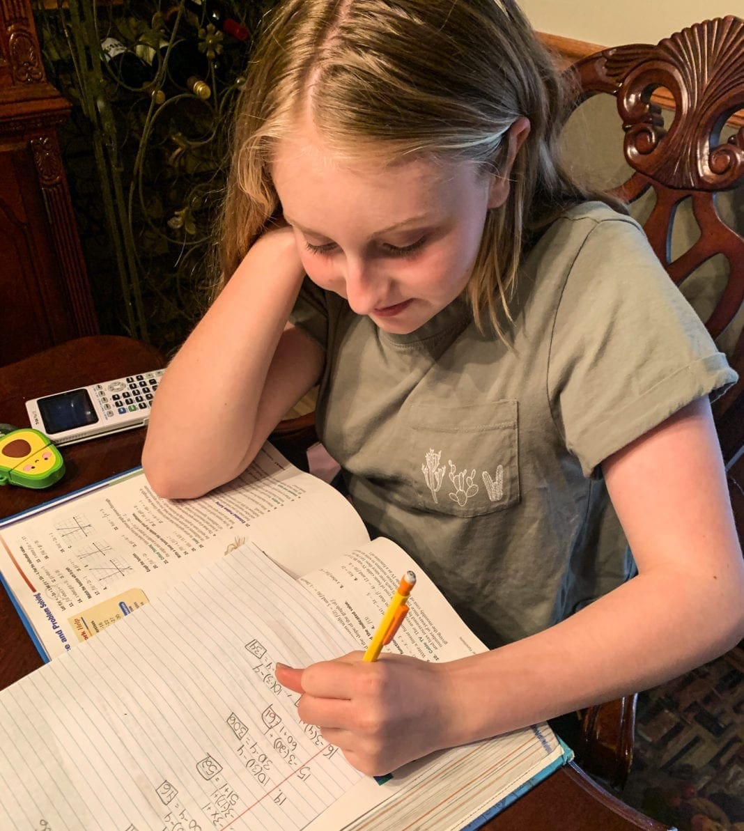 A child doing schoolwork on the dining room table.