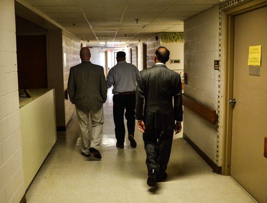 Three men walking down a hospital hallway.