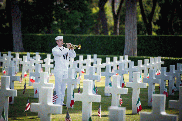 A sailor playing a trumpet in a cemetery.