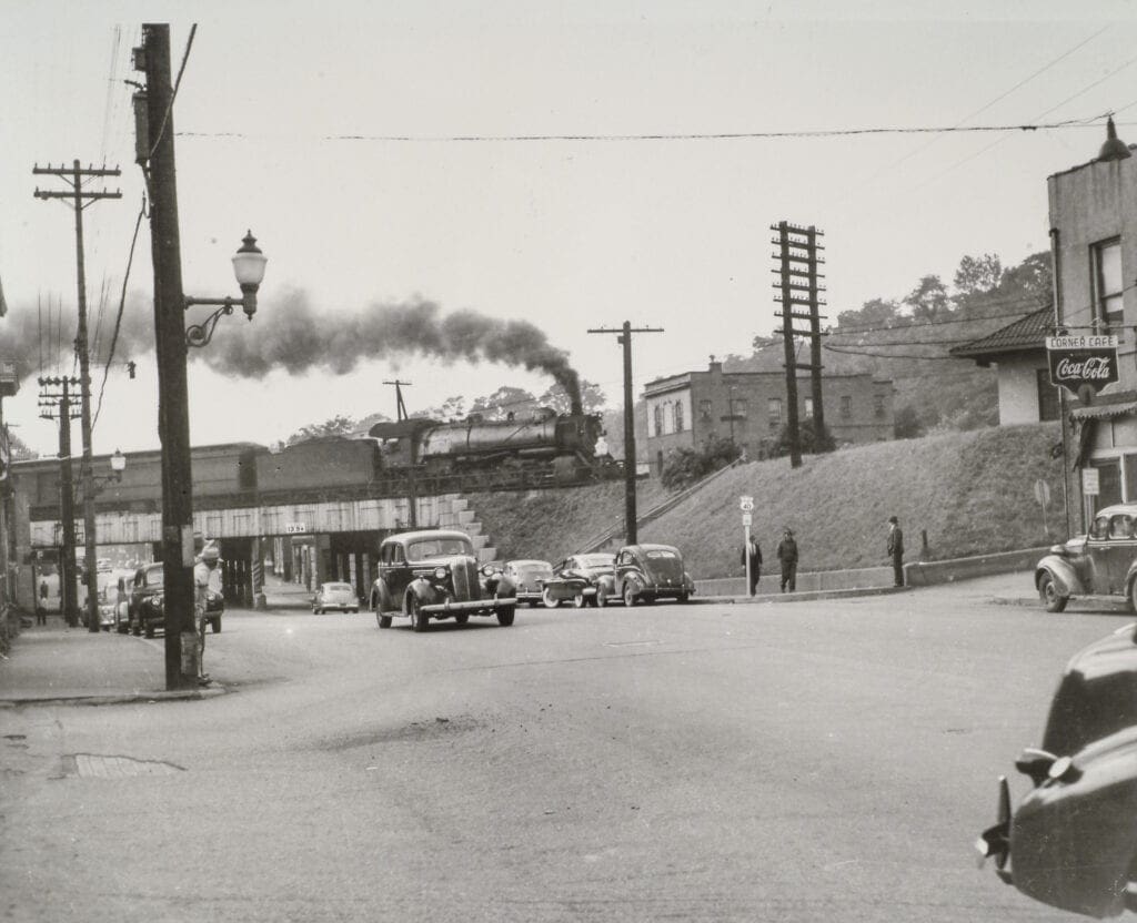 A photo of a train traveling above a roadway.