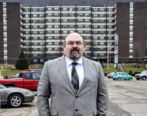 A man standing in front of an apartment building.