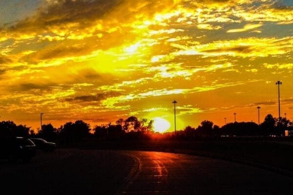 A photo of a sunset over a rural roadway.