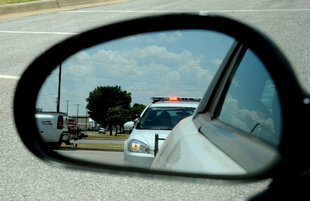 A photo of a mirror with a police cruiser in it.