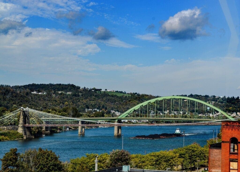 A photo of a barge going under an interstate bridge.