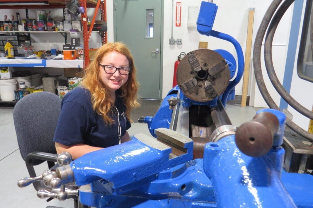 A young lady working with a machine tool.