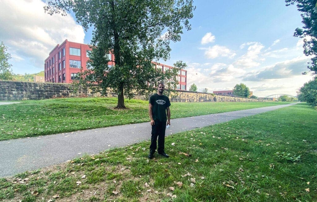 A man standing along an asphalt sidewalk.