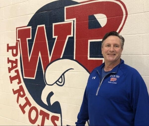 A photo of a man in front of a logo.