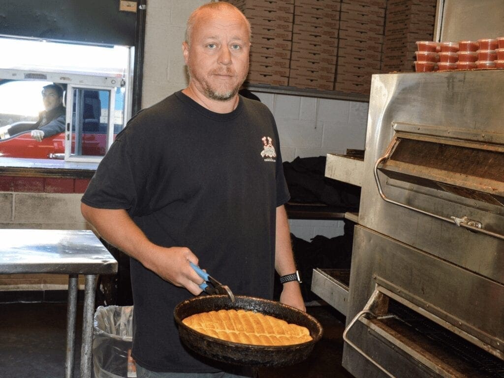 A man holding a pan of bread.