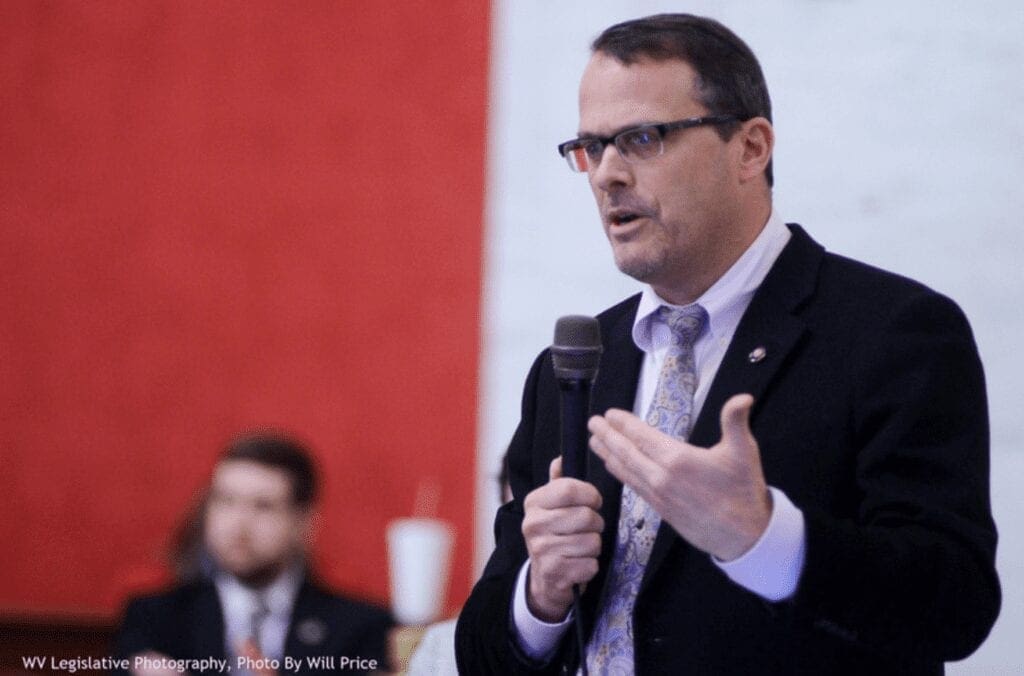 A man standing with a microphone and speaking.