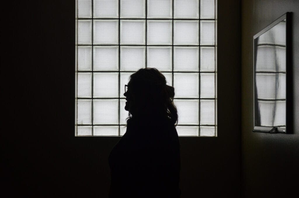 A woman standing in front of a window.