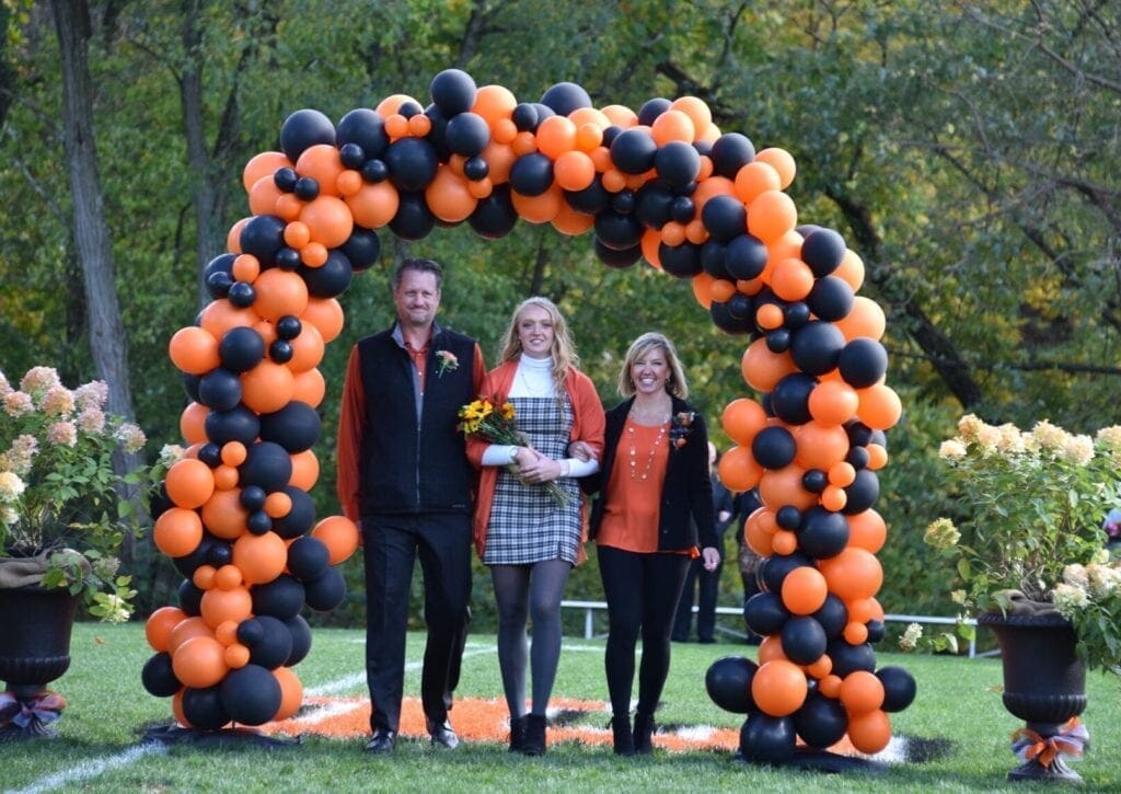 A family of three walking through a balloon tunnel.