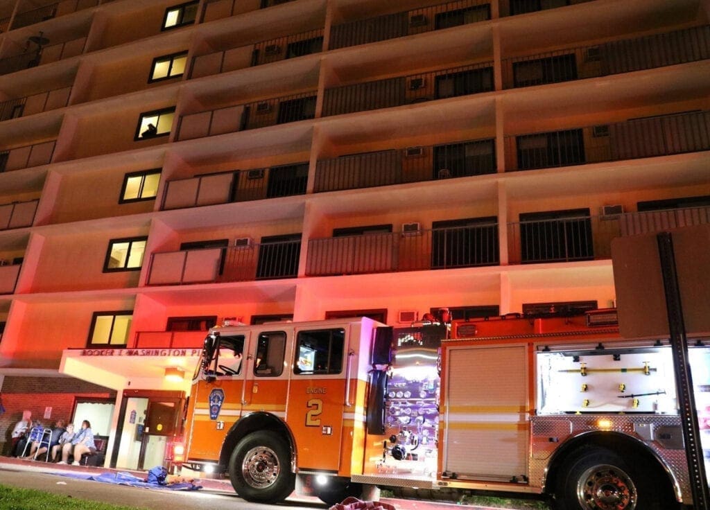 A fire truck in front of a highrise.