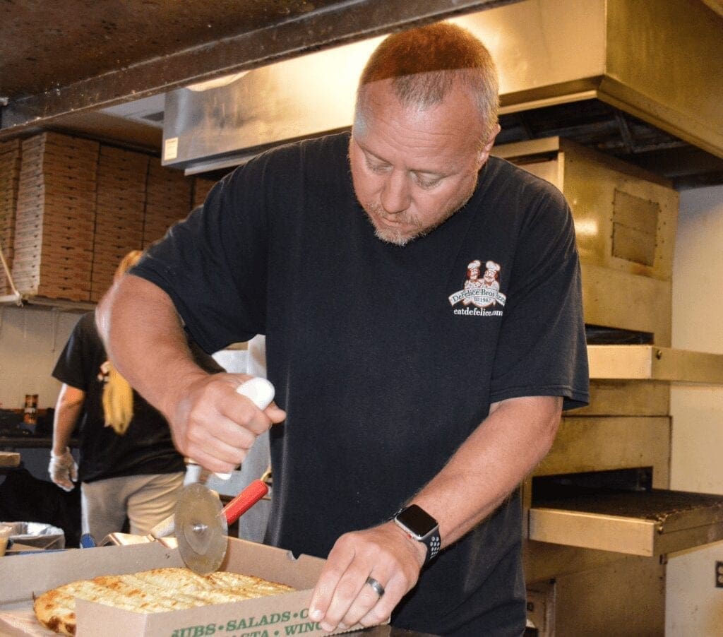 A man slicing cheesy bread.