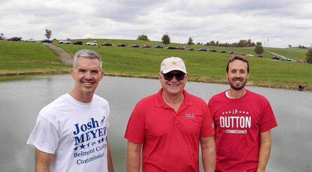 Three men in front of a lake.