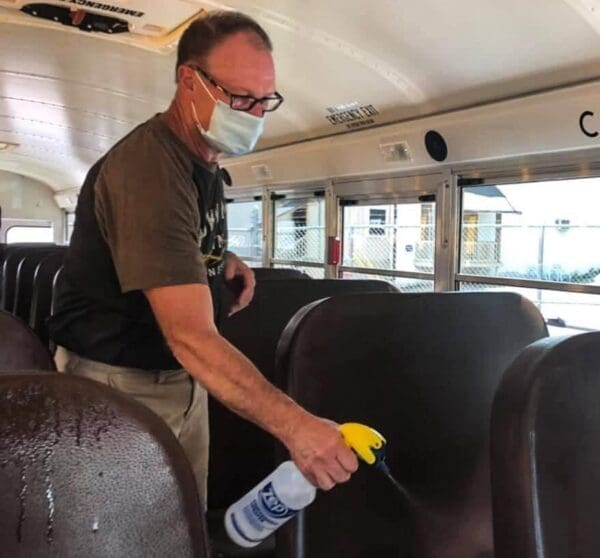 A man in a masking spraying disinfectant.