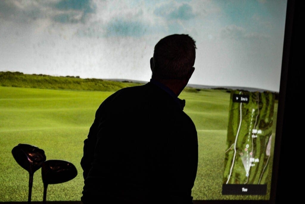 The silhouette of a man playing indoor golf.