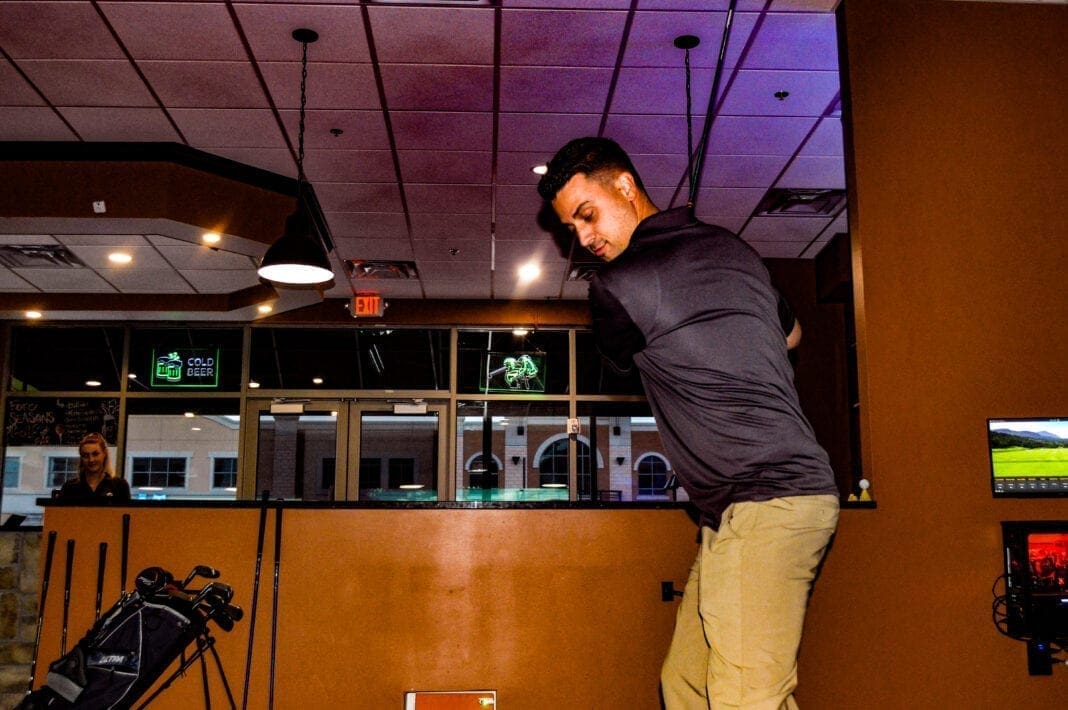 A man swinging a golf club indoors.