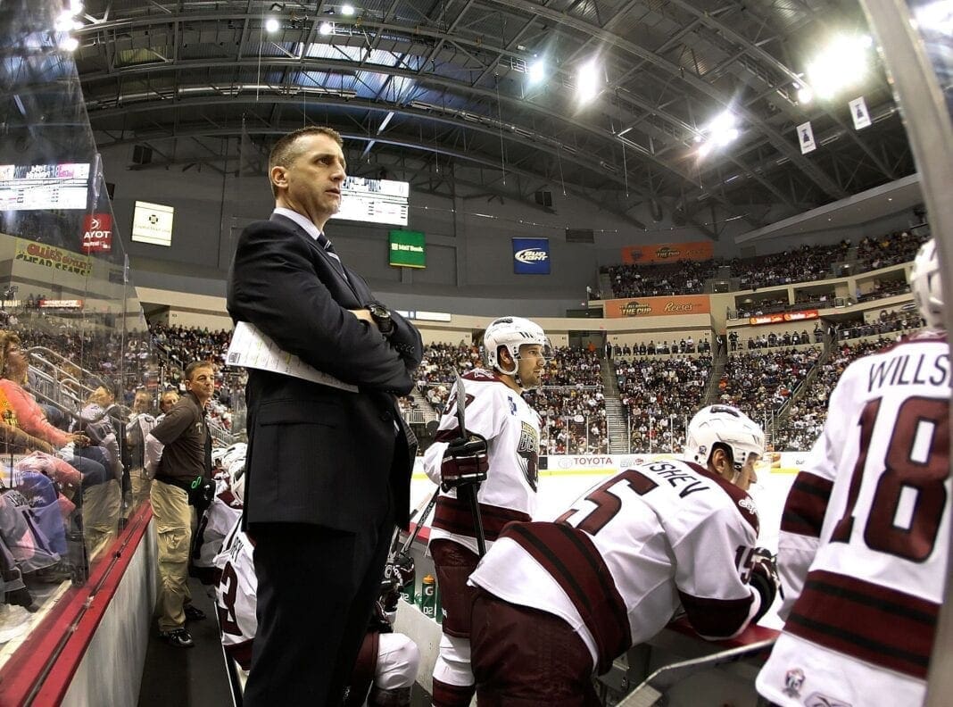 A hockey coach behind his bench.