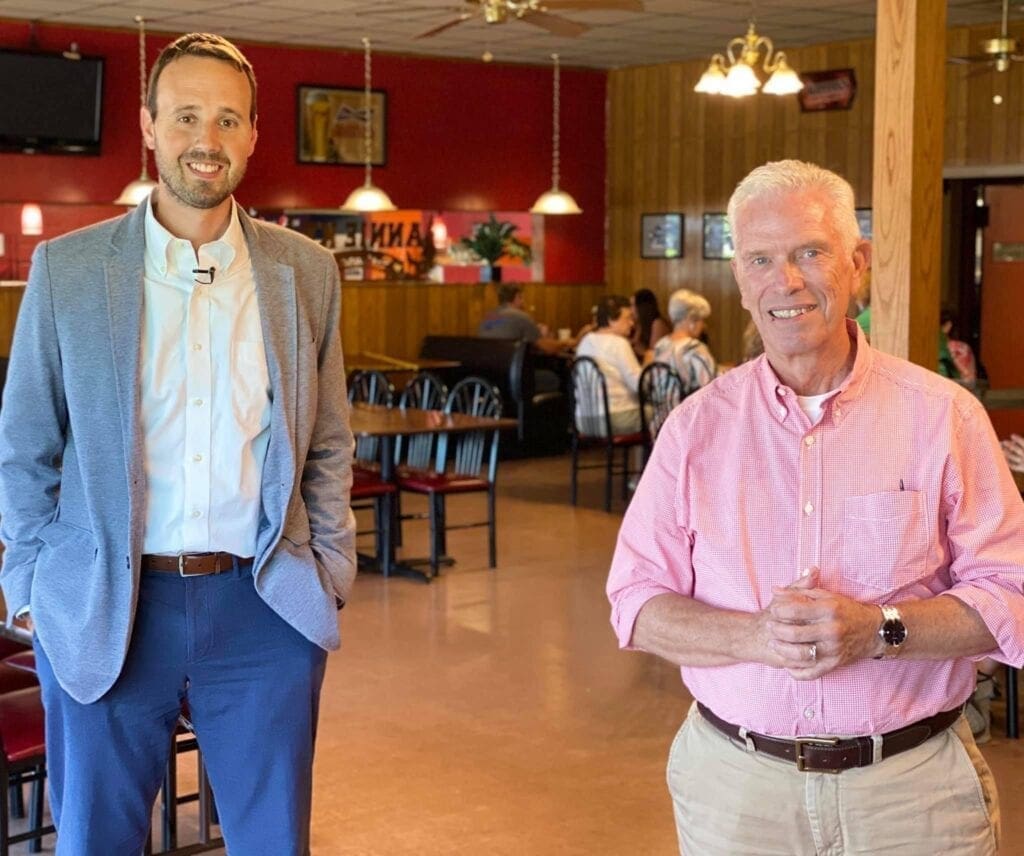 Two men standing in a restaurant.