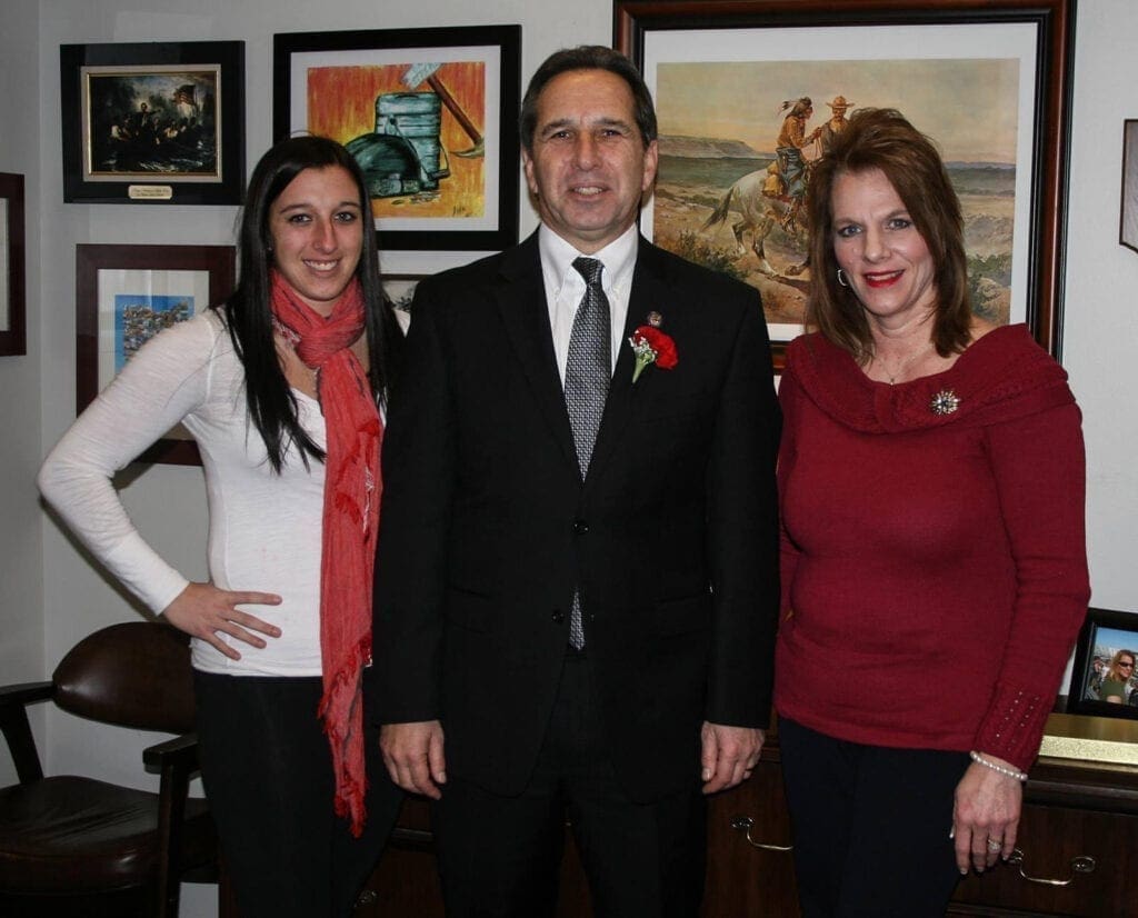 A man in a suit with two ladies surrounding him.