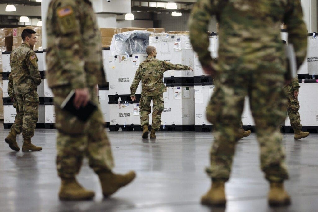 Men in fatigues in a warehouse.