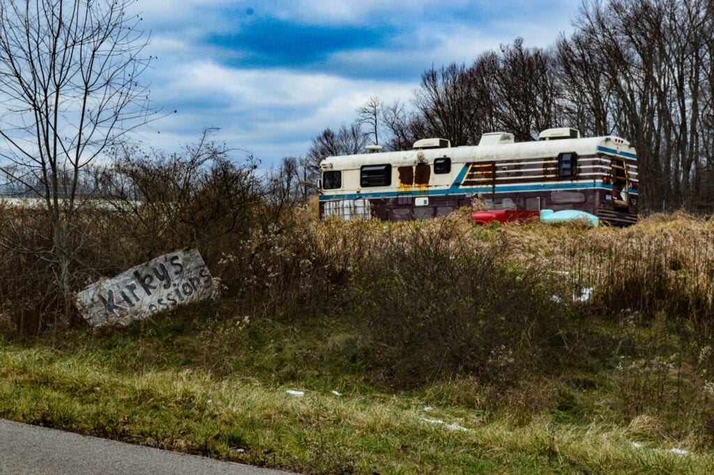 An old bus with several air conditing units on top.