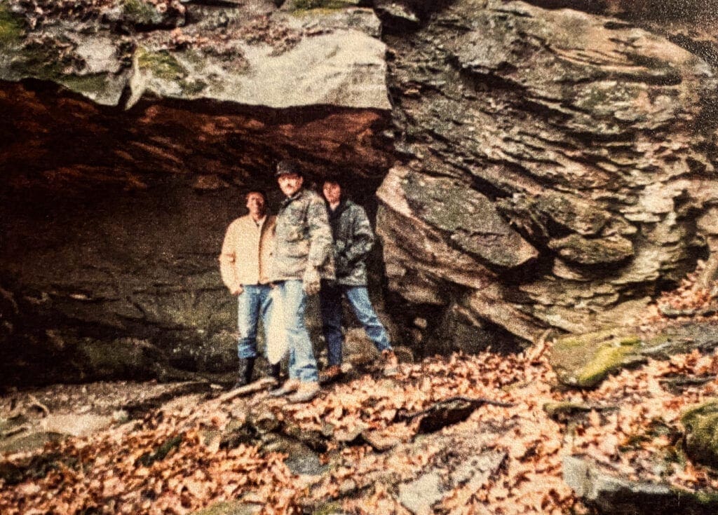 Three people in front of a cave.