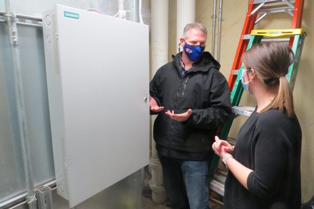 Two people looking at an HVAC system.